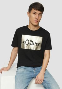 Schwarzes Baumwoll-T-Shirt mit einer goldmetallicfarbenen rechteckigen Grafik, die den Text "s.Oliver." zeigt. Gestylt mit kurzen Ärmeln und Rundhalsausschnitt.
