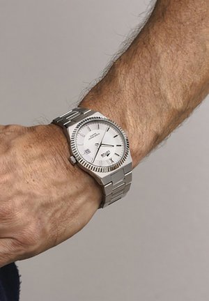 Orologio in acciaio inox argentato con quadrante bianco, indicatori delle ore argentati e finestra della data. Presenta una lunetta lucida e un bracciale a maglie.