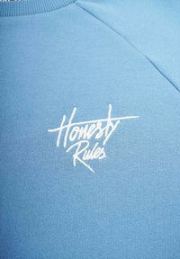 Sininen huppari, joka on valmistettu pehmeästä kankaasta ja jossa on valkoinen brodeerattu "Honestly Rules" -logo edessä. Pyöreä kaula-aukko, jossa on ribbireunus.