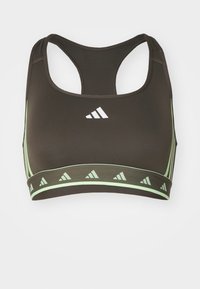Sport-BH i mørkebrunt stoff med en glat tekstur. Har en lys grønn kant og detaljer, trekantet logo-mønster og racerback-design.