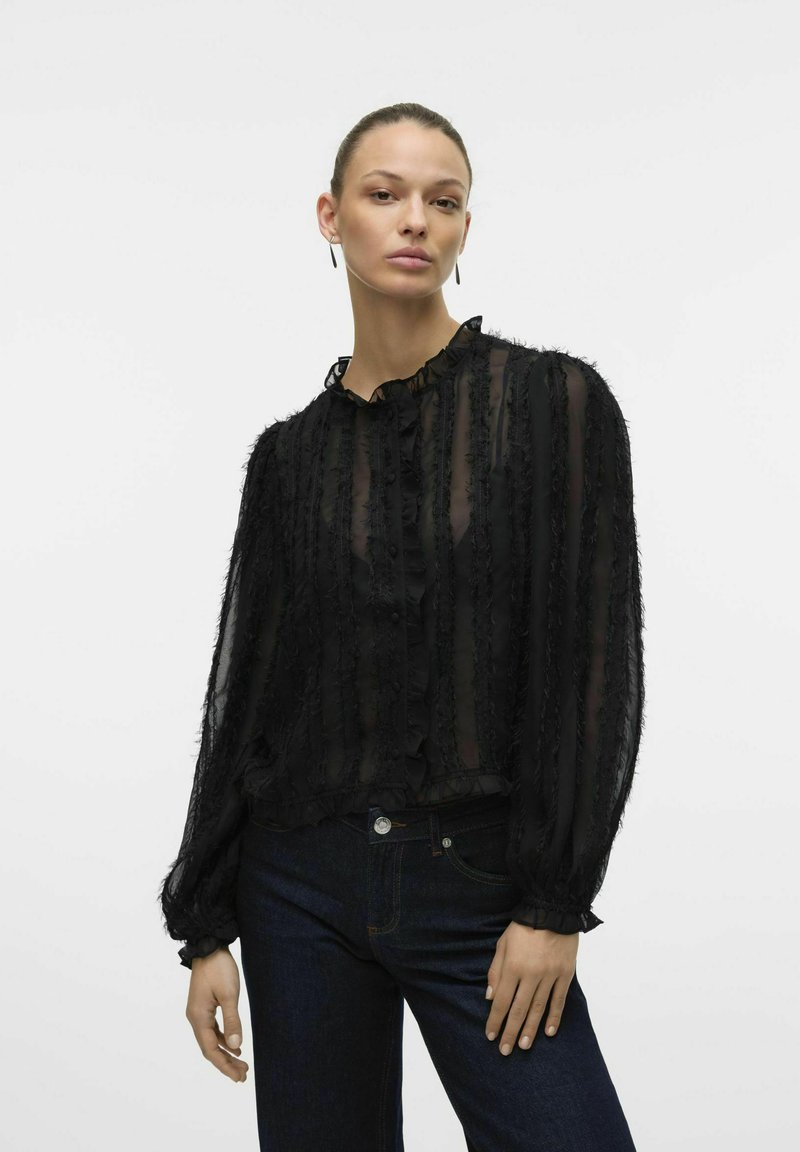 Must musta blouse volangidega ees, nööbiga kinnitus ja pikad puffvarrukad. Omab volangiga kaelaosa ja tekstuurilisi paneele. Sobib tumedate teksadega.