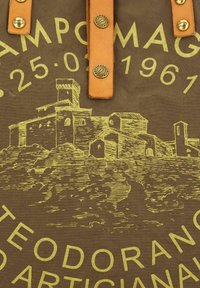 Borsa in tela marrone con grafica gialla di un castello e edifici, con manici in pelle color cuoio e dettagli in ottone.