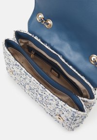 Petit sac à main en tweed bleu et blanc avec intérieur en cuir bleu, détails en chaîne dorée et doublure en tissu beige avec poche intérieure zippée.