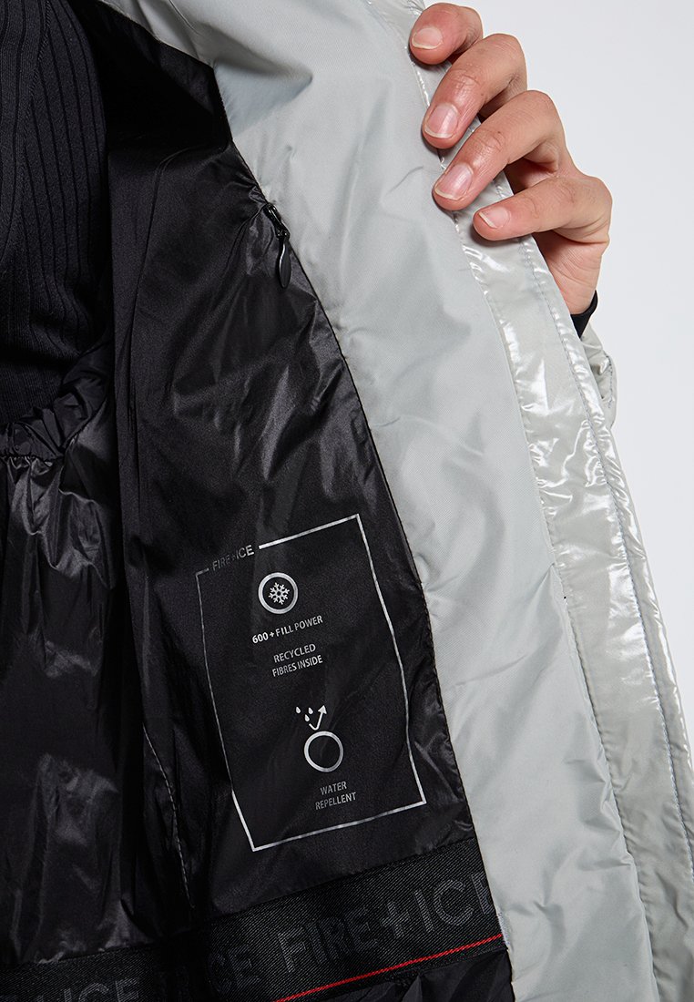 Silberne isolierte Jacke mit schwarzem Innenfutter, ausgestattet mit Etiketten für die Füllkraft, recycelte Fasern und Wasserabweisende Eigenschaften.