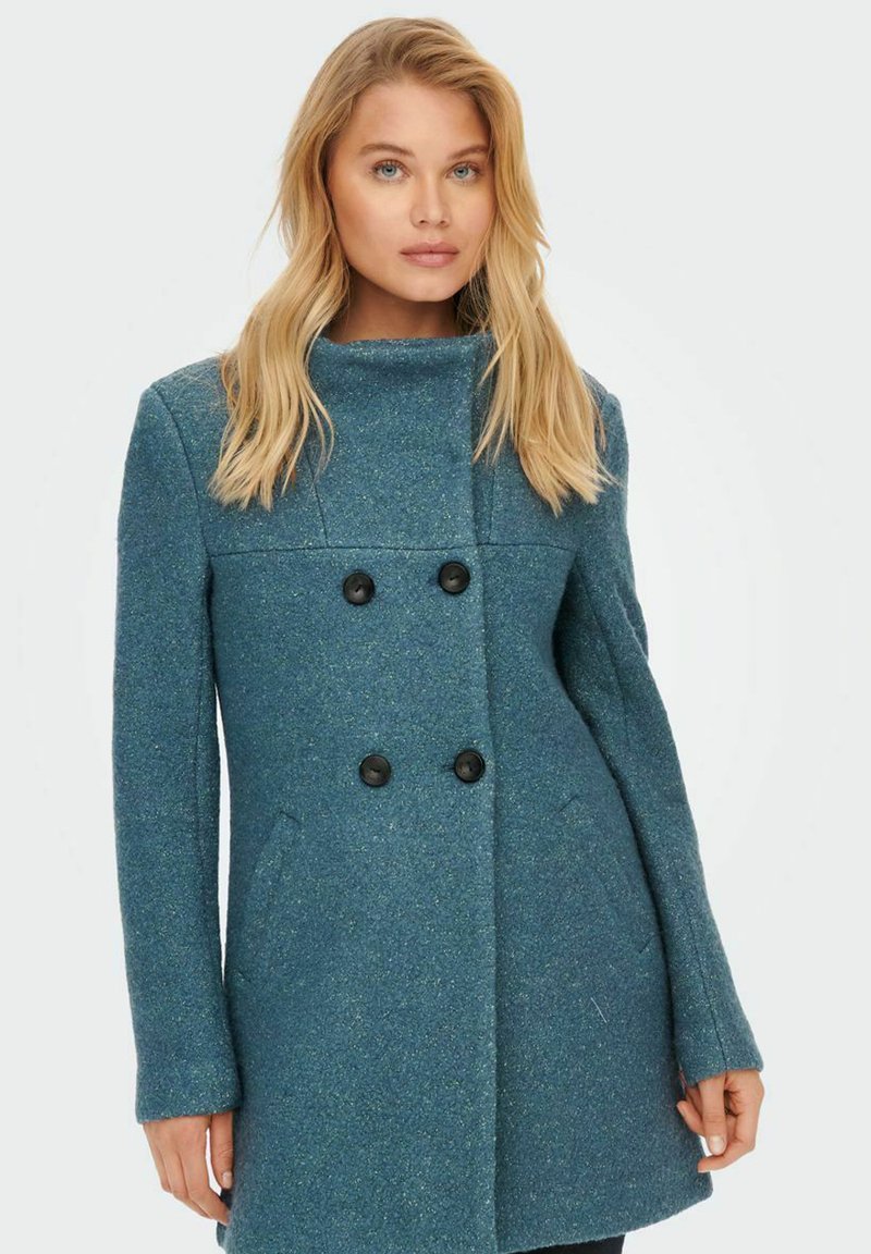 Doppelreiher-Tealfarbe Mantel aus strukturiertem Stoff, mit schwarzen Knöpfen und seitlichen Taschen, ausgestattet mit einem hohen Kragen.