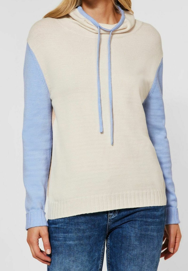 Stickad hoodie med en krämfärgad kropp och ljusblå ärmar, med en cowl-hals, dragsko och ribbad nederkant. Mjuk textur, avslappnad passform.