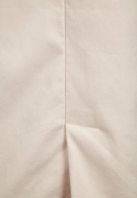 Ljusbeige tyg med en mjuk textur, med en söm i mitten och en liten veck längst ner för designens skull.