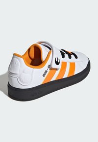 Baskets blanches avec des rayures orange, lacets noirs et une sangle, dotées d'une semelle noire texturée et d'un design BB-8 en relief sur le talon.