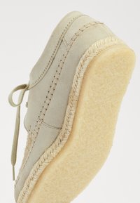 Lichtbeige schoen met een zachte suède bovenkant, vetersluiting en een dikke, gestructureerde espadrille-achtige zool versierd met een gevlochten rand.