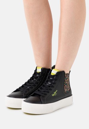 Zapatillas negras de caña alta hechas de cuero texturizado, con un detalle de estampado de leopardo, suela de goma blanca y detalles amarillos contrastantes.