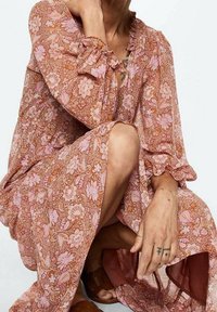 Kleid mit floralem Muster in Pink- und Orangetönen, mit langen Ärmeln und Rüschensäumen. Leichtes Material mit lockerer Passform.