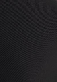 Černá žebrovaná textura látky s jemnými vertikálními pruhy vytvářejícími subtilní vzor a mírným zakřiveným stínováním.