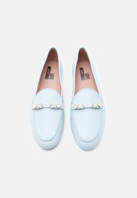 Φως μπλε δερμάτινα μοκασίνια με χρυσές αγκράφες σε σχήμα καρδιάς και το λογότυπο "LOVE MOSCHINO" τυπωμένο στο εσωτερικό πάνω σε παστέλ ροζ εσωτερικές σόλες.