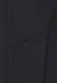 Close-up of black fabric with vertical seams and a small hidden pocket with stitching details.