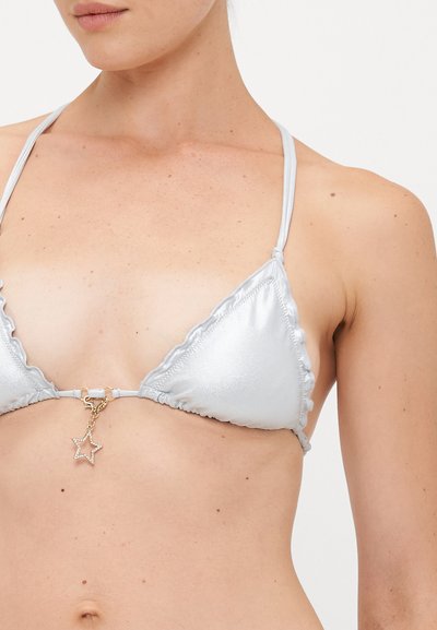 Woman wearing a silver triangle bikini top with thin straps and a small star-shaped charm hanging at the center.