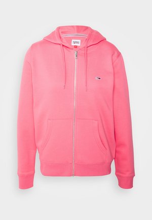 Haut à zip rose en tissu doux, avec une capuche à cordon de serrage, des poches avant et un petit logo sur la poitrine.