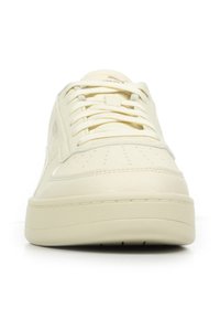 Sneaker in pelle color avorio con lacci tono su tono, punta perforata e linguetta con marchio, vista frontale su uno sfondo bianco.