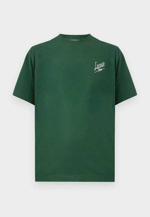 T-shirt en coton vert avec un col rond, des manches courtes et un logo texte "Lacoste Paris" blanc sur la partie gauche de la poitrine.