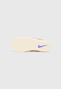 Nike sneaker talpája, texturált gumi geometriával. Krémszínű, lila Nike logóval. Simán csiszolt élek és megerősített sarok.