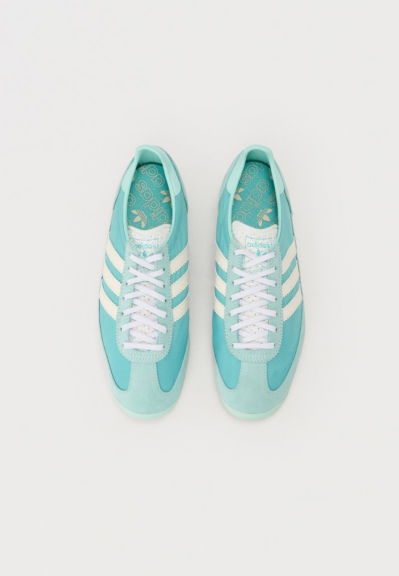 Zapatillas bajas turquesa con tres franjas blancas y cordones. Fabricadas de un material suave con una puntera texturizada. Logo en la lengüeta.