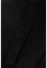 Črni semiš z mehko teksturo, na katerem je pravokoten obliž. Površina je enakomerna z rahlimi odtenki.