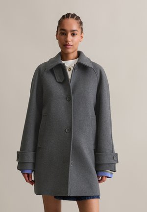 Grijze wollen jas met een kraag, voorknopsluiting en zijzakken. Heeft oversized manchetten met knoopaccenten en een ontspannen pasvorm.