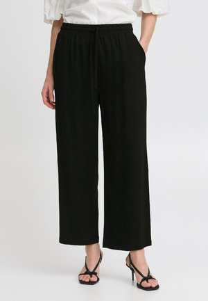 Pantalons larges noirs avec une taille élastique et un cordon de serrage. Poches latérales, fabriqués en tissu doux, avec une texture lisse.