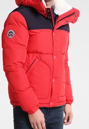 Rote und schwarze wattierte Winterjacke mit Fleecekragen, vorderen Druckknöpfen, Reißverschlusstaschen und Logo-Patch am linken Ärmel.