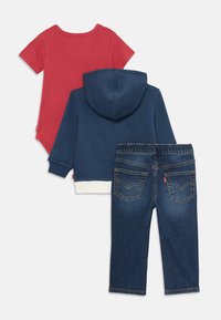 Set de îmbrăcăminte pentru copii din trei piese: un bodystocking roșu cu mânecă scurtă, un hanorac bleumarin cu glugă și pantaloni din denim închis cu buzunare la spate.