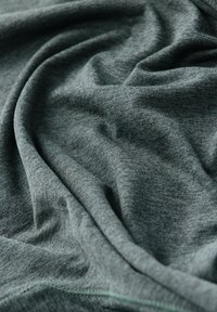 Μαλακό γκρι ύφασμα με λεπτή υφή και απαλά πτυχώσεις που δημιουργούν ένα ομαλό, ρέον μοτίβο.