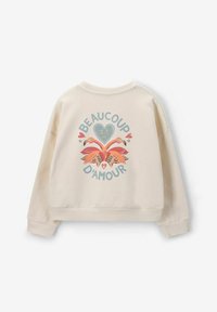 Sweatshirt couleur crème avec une coupe décontractée, présentant un graphique vibrant de deux flamants roses et le texte "BEAUCOUP D'AMOUR" dans le dos.