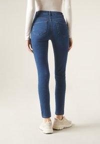 Smal jeans i denim, med två bakfickor och en åtsittande design. Bärs med ljusa sneakers.