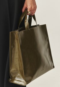 Olivgrüne Leder-Shopper-Tasche mit glatter Textur, rechteckiger Form und doppelten Griffen. Verfügt über dezente Markenkennzeichnung an der Seite.