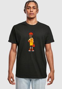 Sort t-shirt med et grafisk motiv af en karakter i en rød hat og gul påklædning, der holder pomfritter, med røde og gule detaljer på skoene.