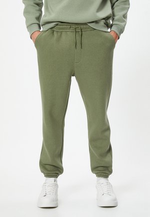 Olivegrüne Sweatpants aus weichem Material mit einem elastischen Bund und Kordelzug, seitlichen Taschen und gerippten Knöchellöchern.