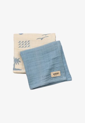 Două bucăți pliabile de pânză de muselină, una albastru solid cu eticheta „WHEAT”, cealaltă bej cu modele tropicale albastre care includ palmieri, valuri și păsări.
