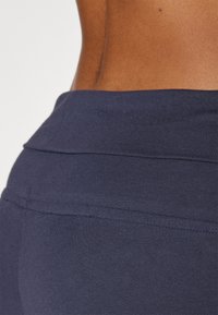 marineblå leggings laget av elastisk stoff med en glattet tekstur; har en bred linning og subtil sømdetaljering.