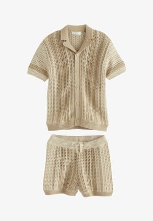 Beige strikket kortærmet skjorte med krave og knapper, parret med matchende shorts. Begge har et tekstureret, stribet mønster.
