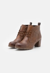 Bruine leren enkelboots met een ronde neus, decoratieve stiksels en een gestapelde hak. Voorzien van vetersluiting en trekjes.