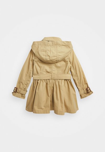Beige huvad jacka med insnörning i midjan, utsvängd nederdel och spänne på ärmarna. Slät tyg med subtil struktur.