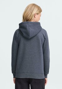 Grå hættebluse med et tekstureret materiale, ribbede manchetter og kant. Har en rummelig hætte og en afslappet pasform, hvilket gør den velegnet til afslappet brug.