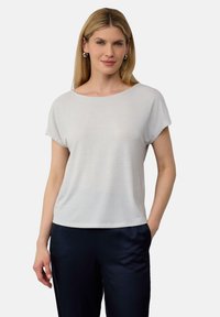 Lichtgrijs kort mouwtop met een losse pasvorm, ronde halslijn, zachte textuur en verlaagde schouders, gecombineerd met donkerblauwe broek.