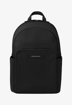 Mochila negra con un tejido texturizado, parte superior redondeada, bolsillo frontal y un asa. Presenta una etiqueta con el logo en el centro frontal.