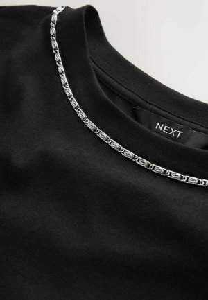 Sort t-shirt med en sølvfarvet dekorativ kæde langs kraven. Blødt stof med struktureret halsudskæring. Brandmærke synligt indvendigt.