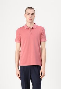 Polo shirt met korte mouwen in lichtroze katoen, met een kraag, een slanke pasvorm en subtiele logo-detail op de borst. Gecombineerd met donkere broek.