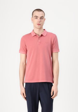 Polo shirt met korte mouwen in lichtroze katoen, met een kraag, een slanke pasvorm en subtiele logo-detail op de borst. Gecombineerd met donkere broek.
