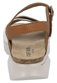Brown leather strap sandal with a white cork-style sole. Features a flat heel, sturdy buckle, and textured footbed. Branding visible.