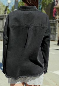 Juodas džinsinis marškiniai su apykakle, nusidėvėjusiu hemu ir tekstūruotu audiniu. Pasižymi nugaros raukiniu ir matomomis siuvimo detalėmis.