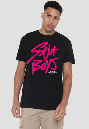Black cotton t-shirt featuring bold, pink graphic text "SAJA BOYS" on the front and "KPOP DEMON HUNTERS" logo. Short sleeves, relaxed fit.