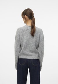 Gray, fluffy knit sweater with a round neck, long sleeves, and ribbed hem. Worn with dark blue denim jeans, showing the back view.